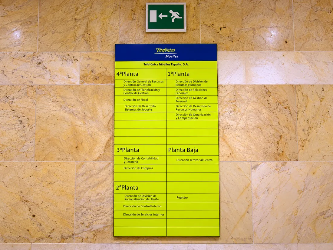 Directorio de plantas de Telefónica Móviles España sobre pared de mármol, con el listado de direcciones por planta.